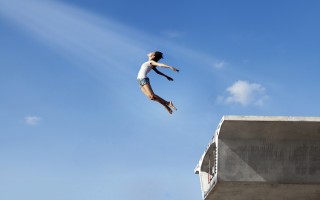 Asian woman flying off the bridge. Shot over clear blue sky.