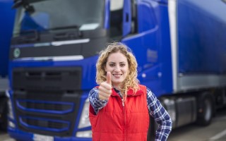 Portrait of professional truck driver showing thumbs up and smiling.