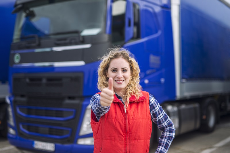 Portrait of professional truck driver showing thumbs up and smiling.